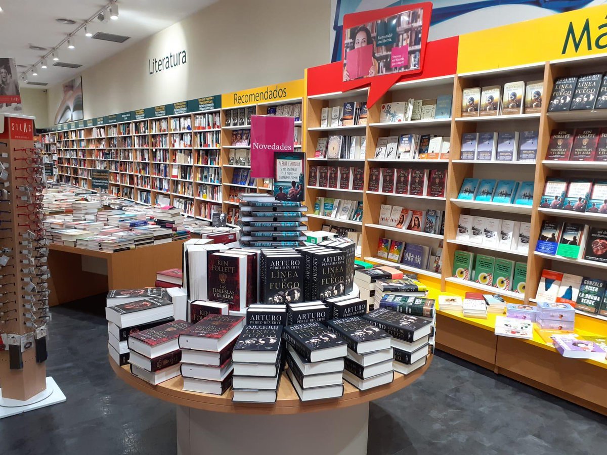 Librería con libros destacados en mesas y estantes.