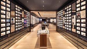 Tienda de gafas con estanterías iluminadas y mostrador.