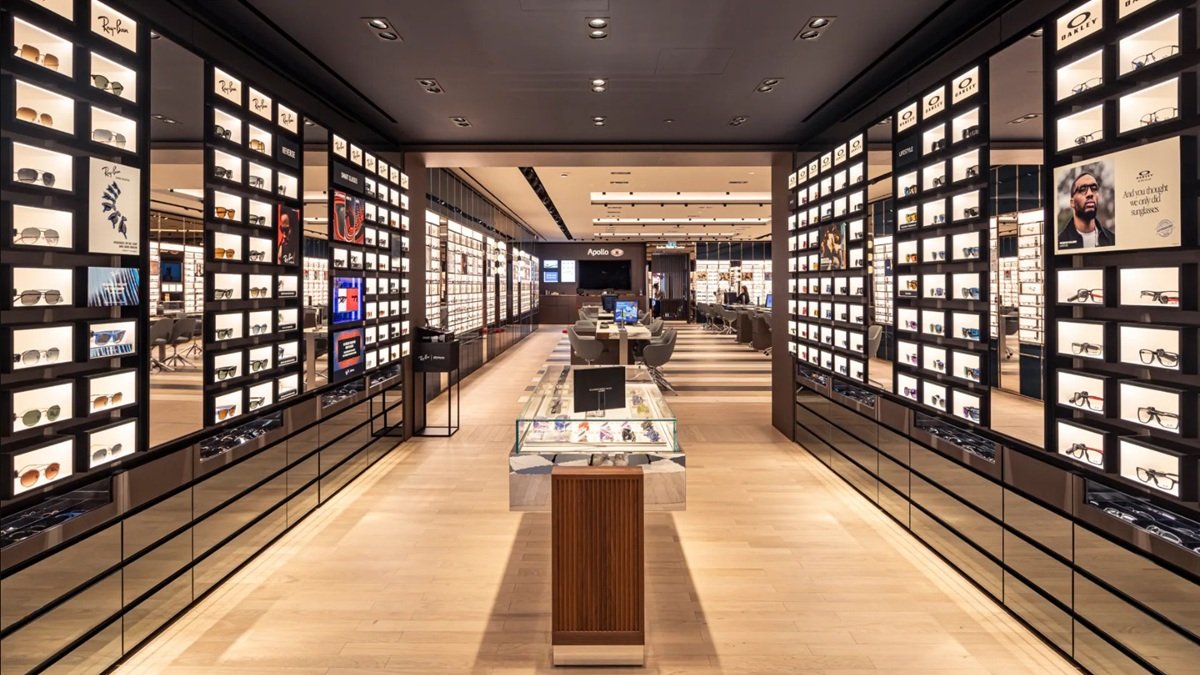 Tienda de gafas con estanterías iluminadas y mostrador.